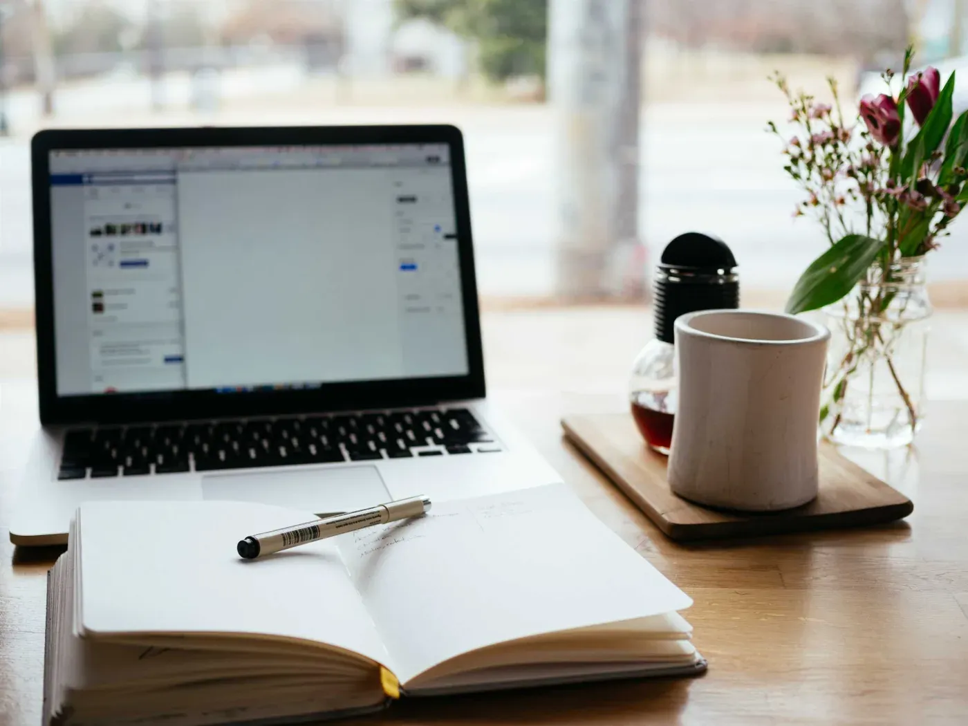 A laptop and open notebook set up for writing on a desk
