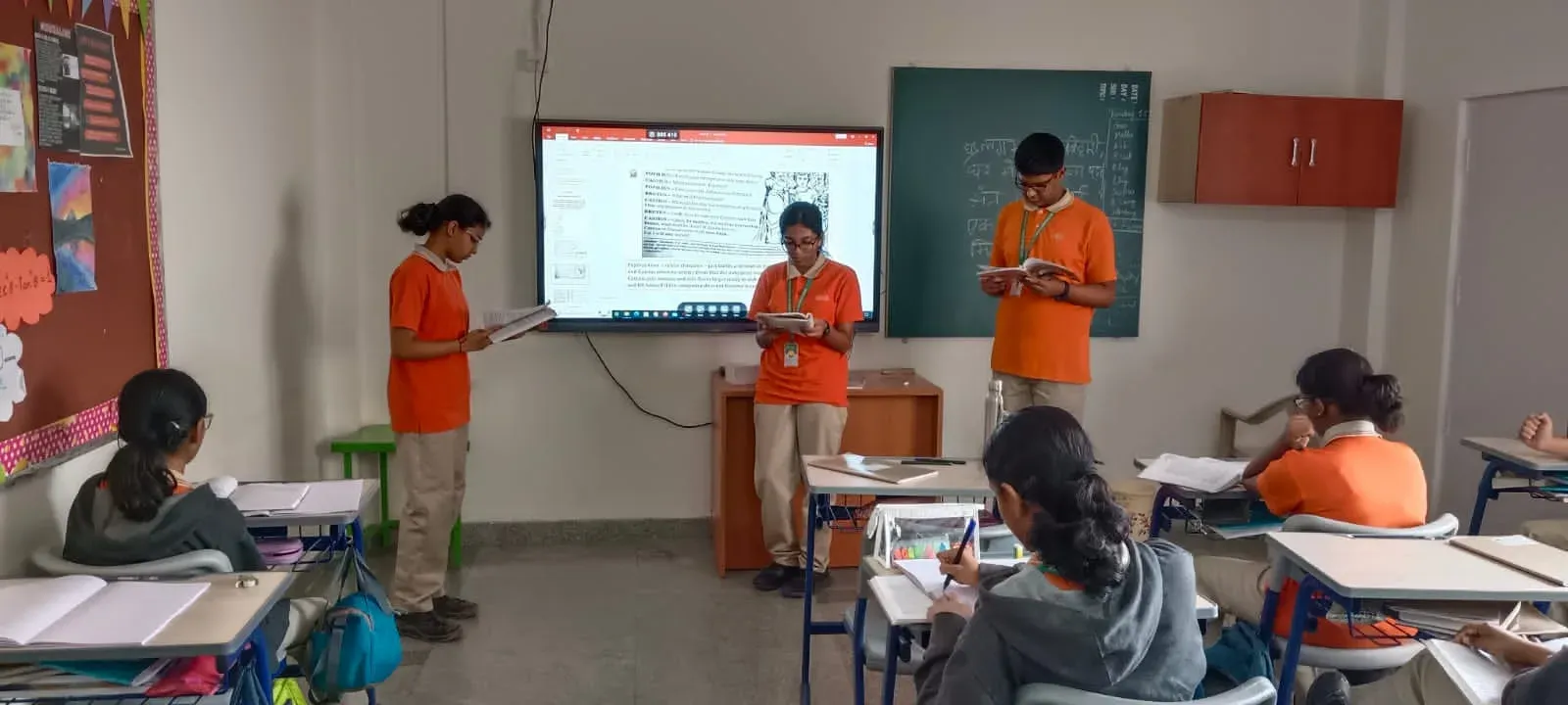 Students presenting at a digital board in the classroom